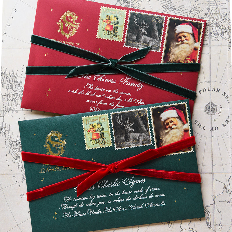 Red and green Santa envelopes tied with velvet ribbon and vintage stamps